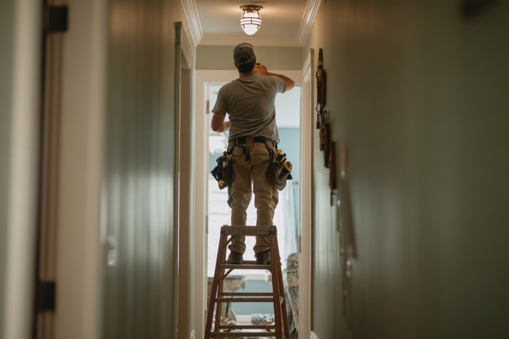 Electrician on a ladder installing a hallway light